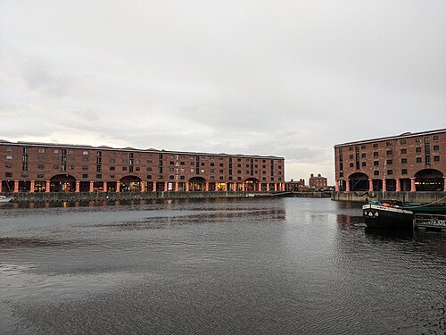 Two warehouse blocks facing each other across the dock, the Tate Liverpool lettering down one gable end, the ground floor arcade of arches and columns along both quays.
