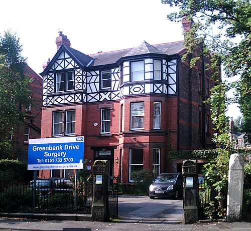 A half timbered and red brick villa on Greenbank Drive, three storeys with a gabled bay, now a doctor's surgery behind its garden wall.