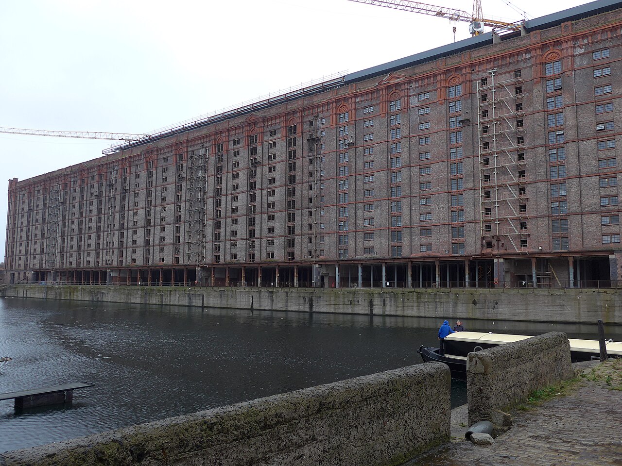 A closer corner view of the Tobacco Warehouse, its ornamental brick pediments and the raised TOBACCO and WAREHOUSE lettering over the top floor, with the grid of red brick piers and darker infill panels running down the face.