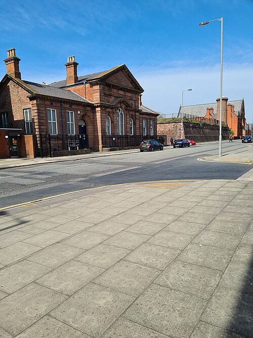 Toxteth Town Hall's single storey red sandstone front on High Park Street, a pedimented centre bay over a round headed doorway, facing a wide paved street.