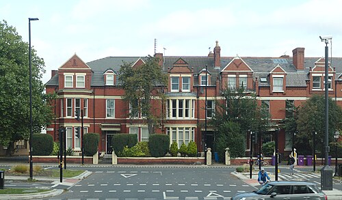 Red brick and stone Victorian terraced villas with bay windows on Princes Avenue, hedges and iron railings along the pavement.