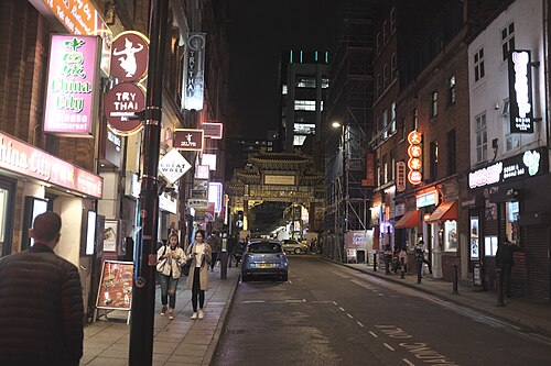 Faulkner Street after dark, neon signs for China City and Try Thai lit along the pavement with the painted arch glowing at the far end.