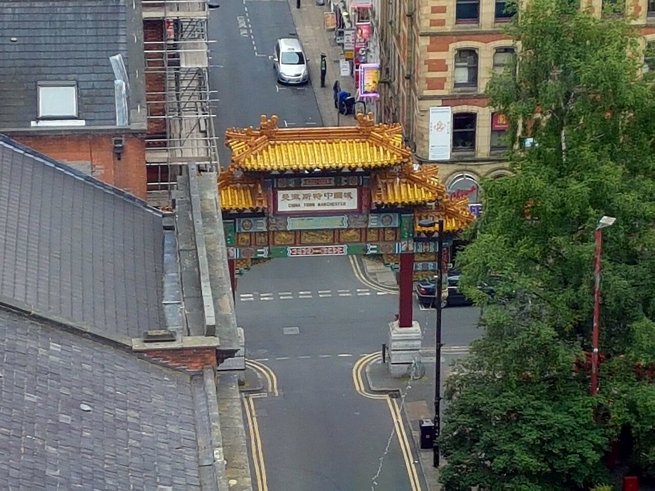 The painted arch and Faulkner Street seen from above, slate roofs and a scaffolded building crowding the street on the approach.