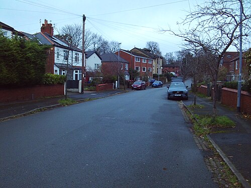 Kingshill Road, another tree lined side street mixing bay windowed Victorian terraces with newer red brick townhouses, overhead wires and parked cars along the carriageway.
