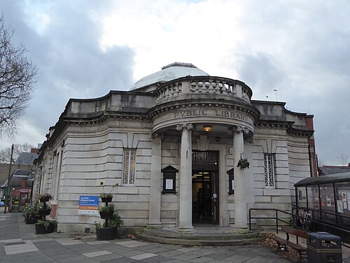 Chorlton Library on Manchester Road, a Portland stone rotunda with paired Ionic columns over the doorway and PUBLIC LIBRARY cut into the frieze below a shallow dome.