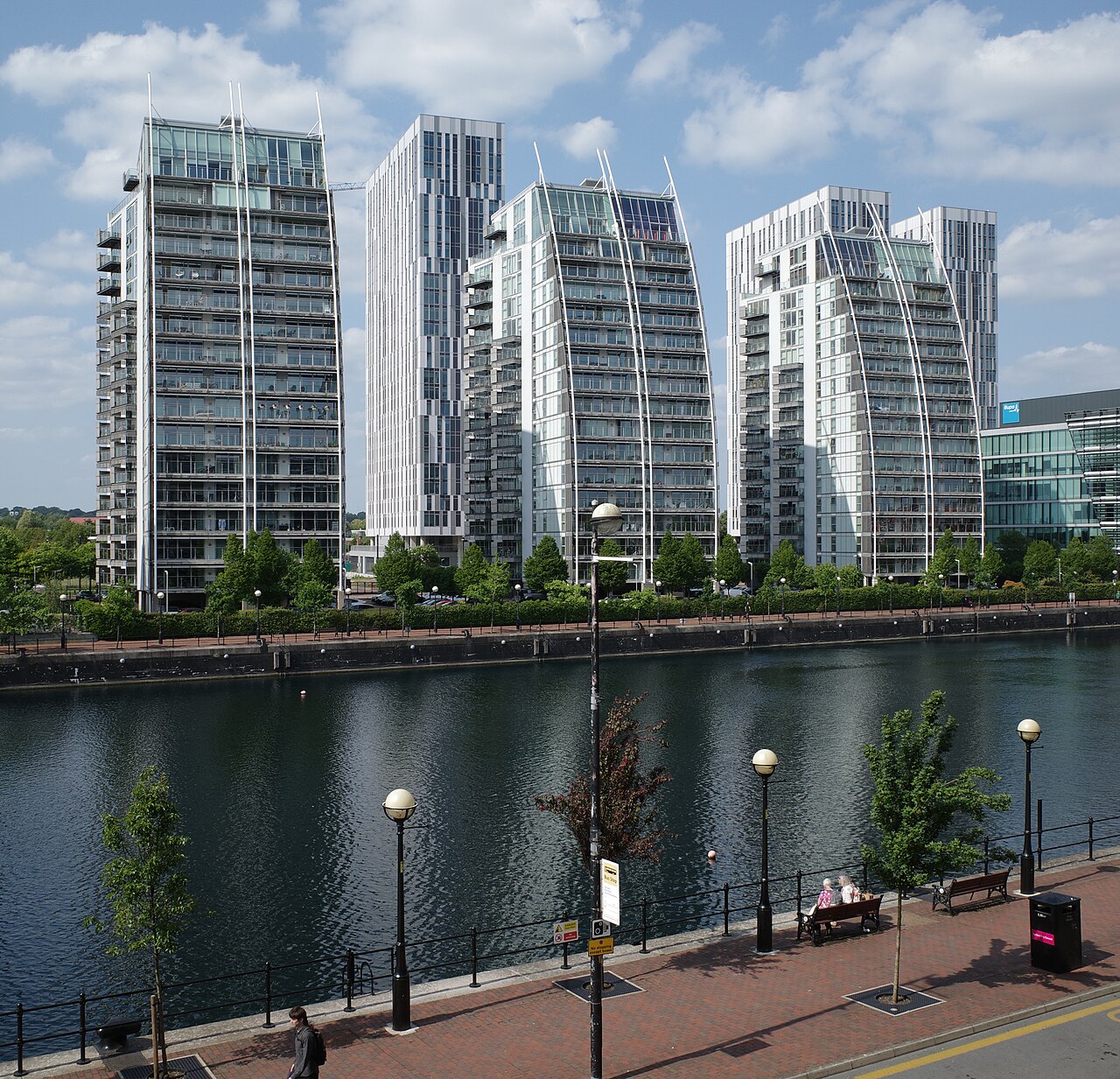 Huron Basin's promenade lined with streetlamps, glass residential towers rising directly off the water on the opposite bank.