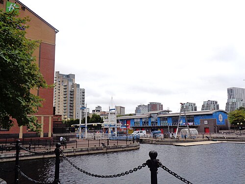 The Agecroft Rowing Club's blue clad boathouse on Ontario Quay, apartment towers behind it across the basin.