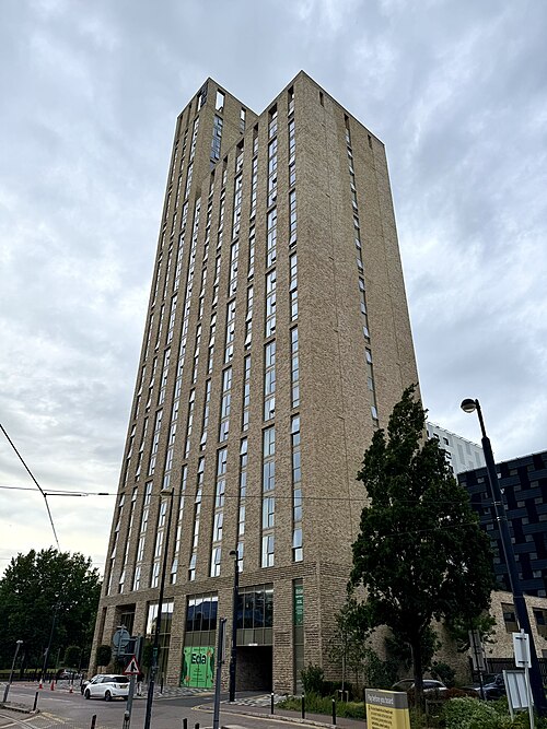 Eda's beige brick tower rising above street level paving and lamp posts on Anchorage Quay.