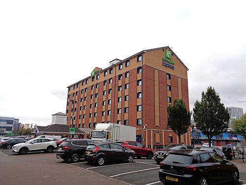The Holiday Inn Express on the edge of the district, red brick with a yellow trimmed upper floor above a surface car park.