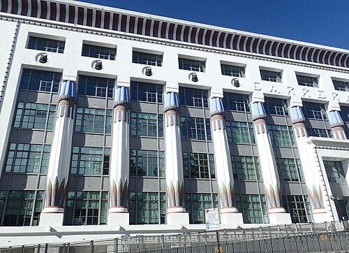 The front of Greater London House, white with painted lotus columns standing clear of the wall and dark discs set above each bay.