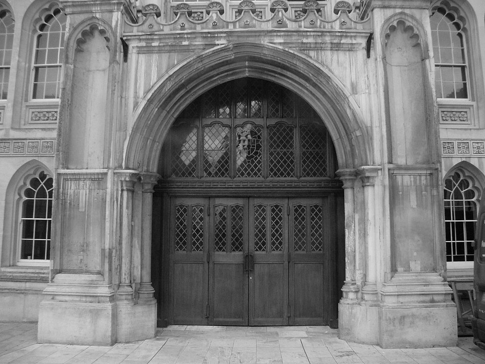 The porch of the Guildhall, a deep stone arch with tracery windows on either side and dark timber double doors under it.