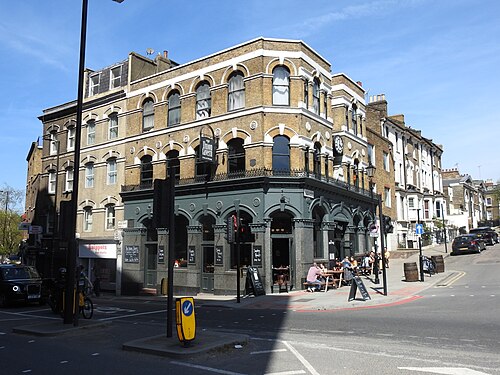 The Union Tavern on the corner of Lloyd Baker Street, yellow brick above a dark green painted ground floor, with tables out on the pavement and a black cab at the junction.