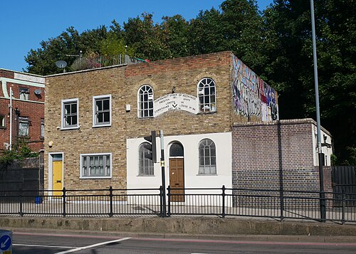 The Independent Order of Mechanics lodge at 335 Wick Road, two storeys of yellow brick with arched windows and a carved stone plaque between them.