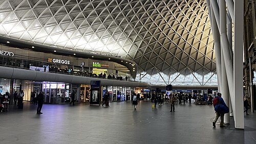 The western concourse at King's Cross, a white steel lattice springing from one point in the floor and fanning out over the whole hall.
