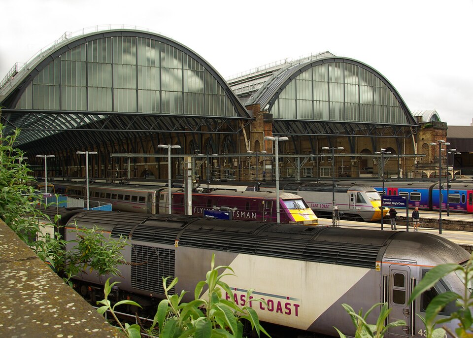 The open north end of King's Cross station, the two arched train sheds side by side with trains standing at the platforms under them.