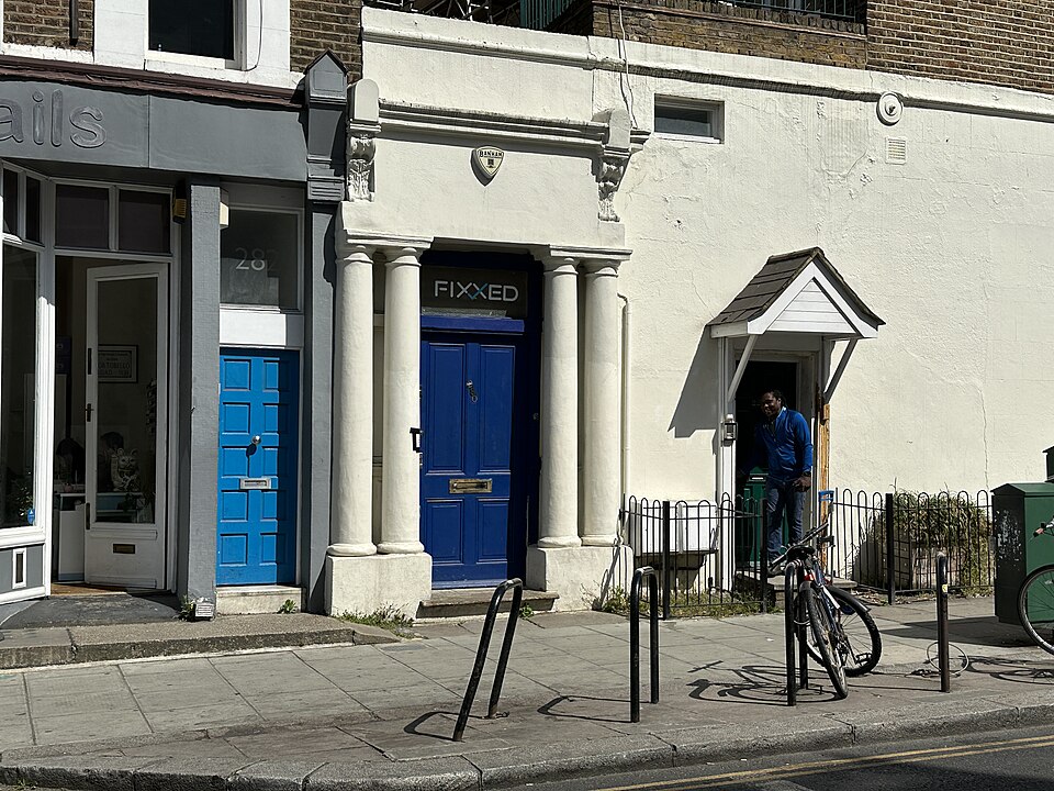 The blue panelled door of 280 Westbourne Park Road in its cream columned portico.
