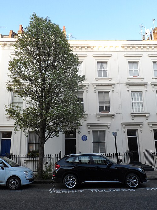 A row of four storey white stucco houses on Ranelagh Road, black iron railings and parked cars along the kerb.