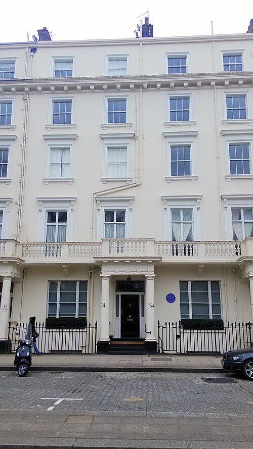 A five storey cream stucco terrace on Eccleston Square, paired columns framing the door and a balustraded balcony along the first floor.
