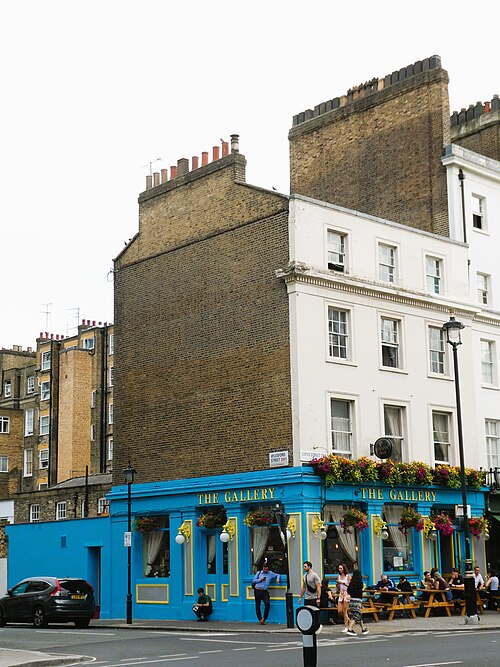 A blue painted Victorian pub on the ground floor of a white stucco corner building, opposite Pimlico Underground station.