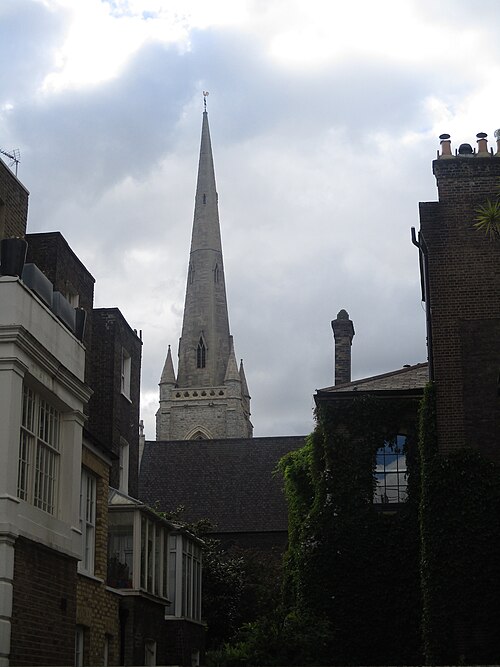 St Gabriel's church spire rising above brick housing and an ivy covered garden wall on Warwick Square.