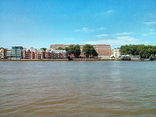 Dolphin Square's red brick blocks seen across the Thames, a glass tower and white stucco terrace beside them on the Pimlico bank.