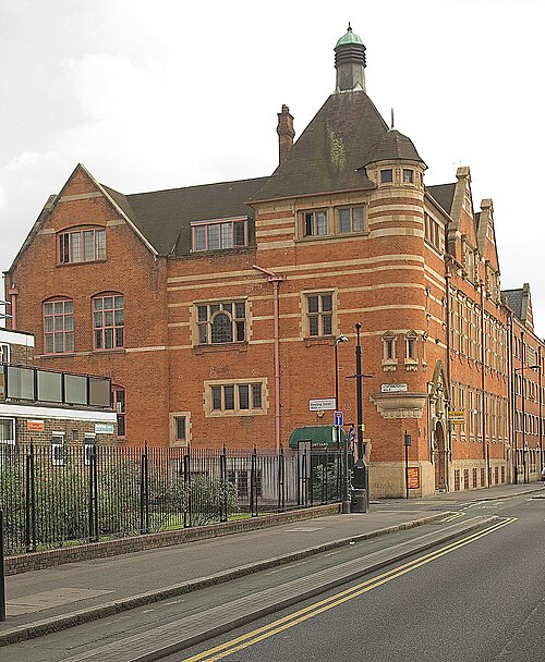 The Passmore Edwards free library on Pitfield Street at Bowling Green Walk, red brick banded with stone and a lead capped turret over the corner.