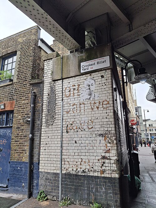 Crooked Billet Yard where it goes under the railway girders beside Kingsland Road, with old lettering showing through the white tiled wall.