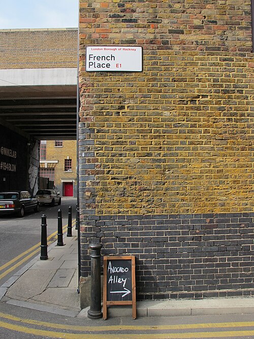 The corner of French Place in yellow stock brick over blue engineering brick, with the railway bridge across the road behind it.