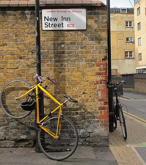 The brick wall at the end of New Inn Street with two bicycles leaning against the lamp posts.
