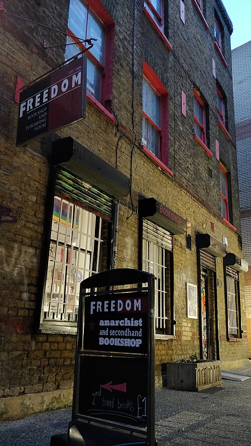 The Freedom Press bookshop in Angel Alley, stock brick with red painted window frames and a hand written board outside.