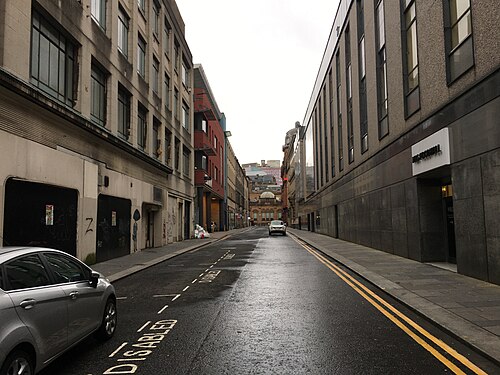 Virginia Street looking north on a wet afternoon, with warehouse walls close on both sides and a domed roofline at the far end.