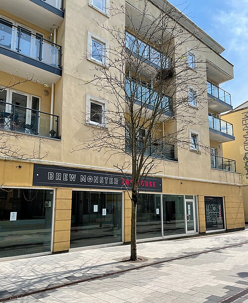A yellow rendered modern building on Bute Street with a taproom shopfront at ground level.
