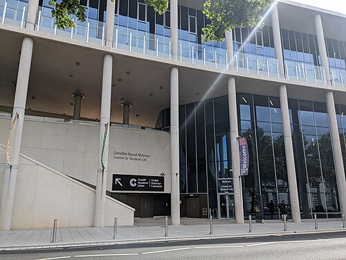 Cardiff University's Students' Union entrance, tall round concrete columns and a glazed upper floor, Centre for Student Life signage over the doors.