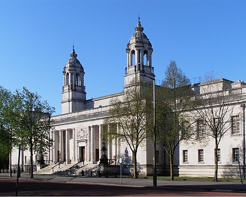 Cardiff Crown Court's columned entrance and twin domed cupola towers against a clear sky, trees along the pavement in front.