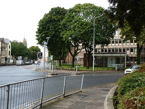The concrete office block at the south end of Cathedral Road, its glazed ground floor entrance under mature trees at the Cowbridge Road East junction.