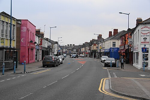 City Road's shopping strip, a pink painted corner building among plainer shopfronts, double yellow lines and street lamps down the middle of the road.