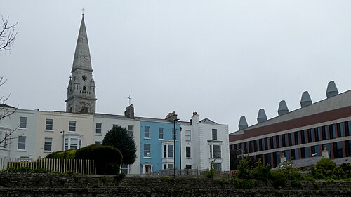 A row of painted stucco terraces with bay windows, beside the modern dlr Lexicon library building.