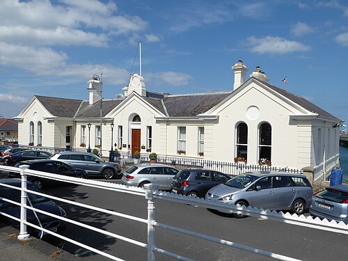 The National Yacht Club, a single storey cream stucco clubhouse with arched windows, a slate roof and white railings.
