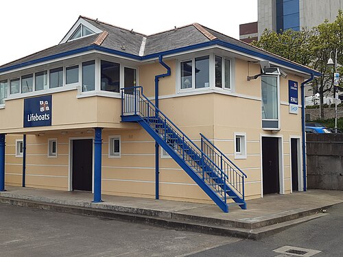The RNLI lifeboat station, a two storey beige building with blue trim and external blue metal stairs.
