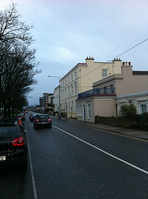 Crofton Road, an asphalt residential street with parked cars running past cream stucco terraced houses.