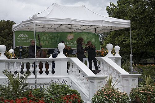 The bandstand in People's Park, musicians playing under a marquee on a white painted stone balustrade.