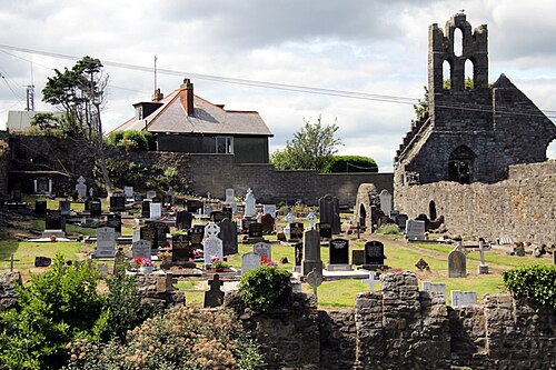 The ruined stone nave of St Mary's standing in its graveyard behind a stone boundary wall.