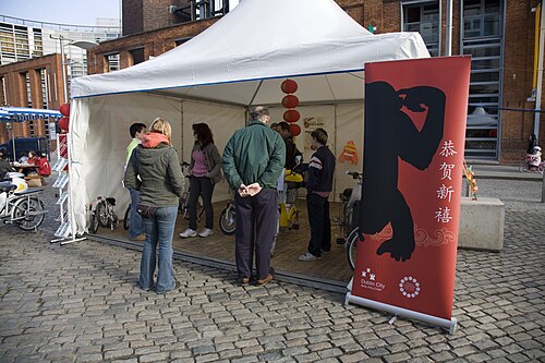 A festival tent set up on the cobbles in front of a red brick building on the square.