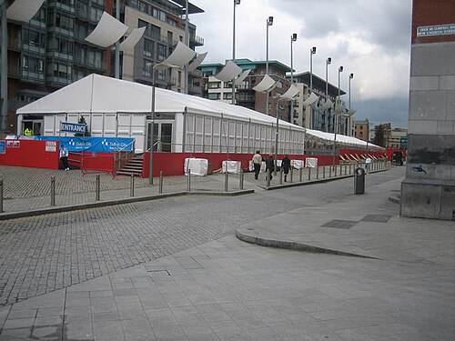 A temporary event tent on the open cobbled square, apartment blocks alongside.