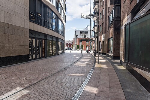 A curved paved street carrying tram tracks between mixed brick and stone buildings at the edge of the square.
