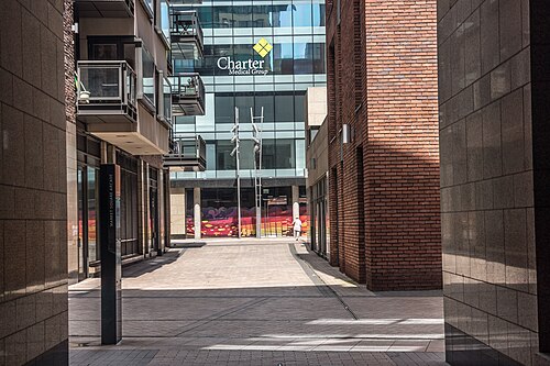 A pedestrian lane between brick and stone buildings, a modern glass office building beyond.