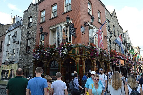 Quays Bar on Temple Bar Square, a green tiled corner front with pedestrians on the cobbles.