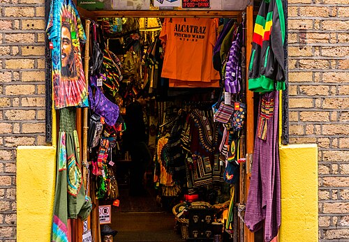 A shop doorway with clothing and souvenirs on display, brickwork painted at the entrance.