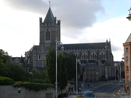 Christ Church Cathedral's stone tower and nave, framed by trees and a decorative lamp post.