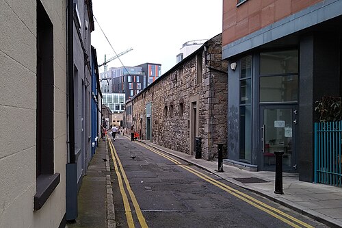 Fumbally Lane, a narrow lane between a stone wall and a brick building.